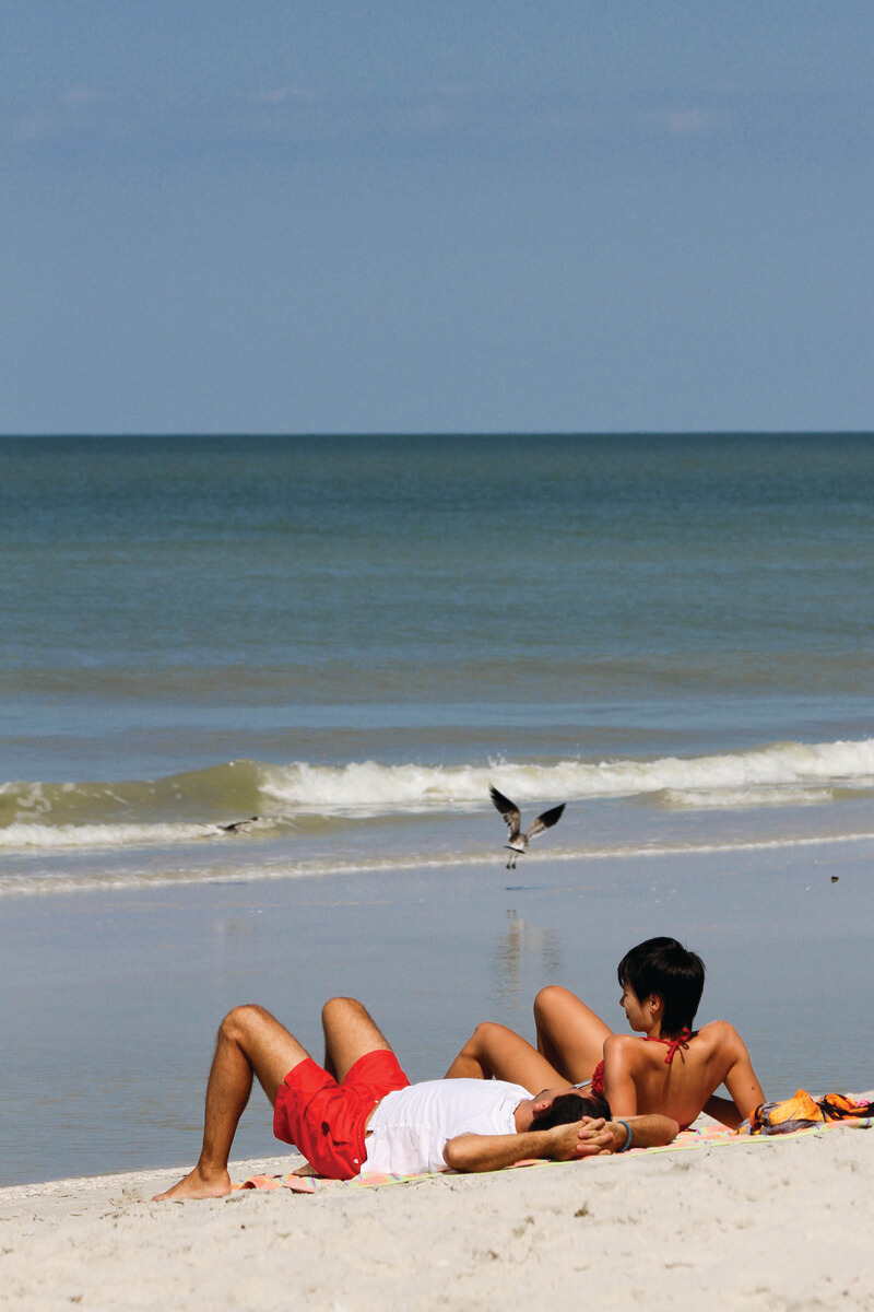 MustDo.com | Couple relax on beach along Gulf of Mexico, Florida, USA. Southwest Florida vacation information and things to do.