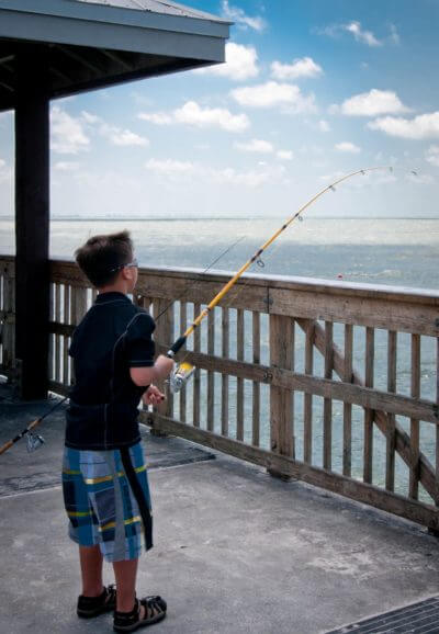 Boy fishing off the Fort Myers Beach Pier Fort Myers, Florida.