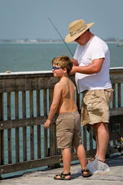 Young boy fishes from the pier with dad Southwest Florida.