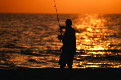 Fisherman casts a line from the beach at sunset in Southwest Florida.
