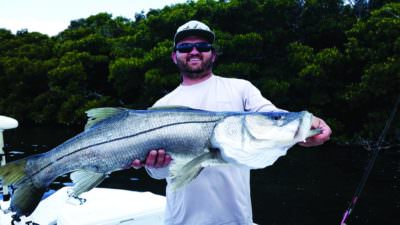 Fisherman shows off his snook catch Southwest Florida. Photo by Elizabeth Lempriere for Must Do Visitor Guides.