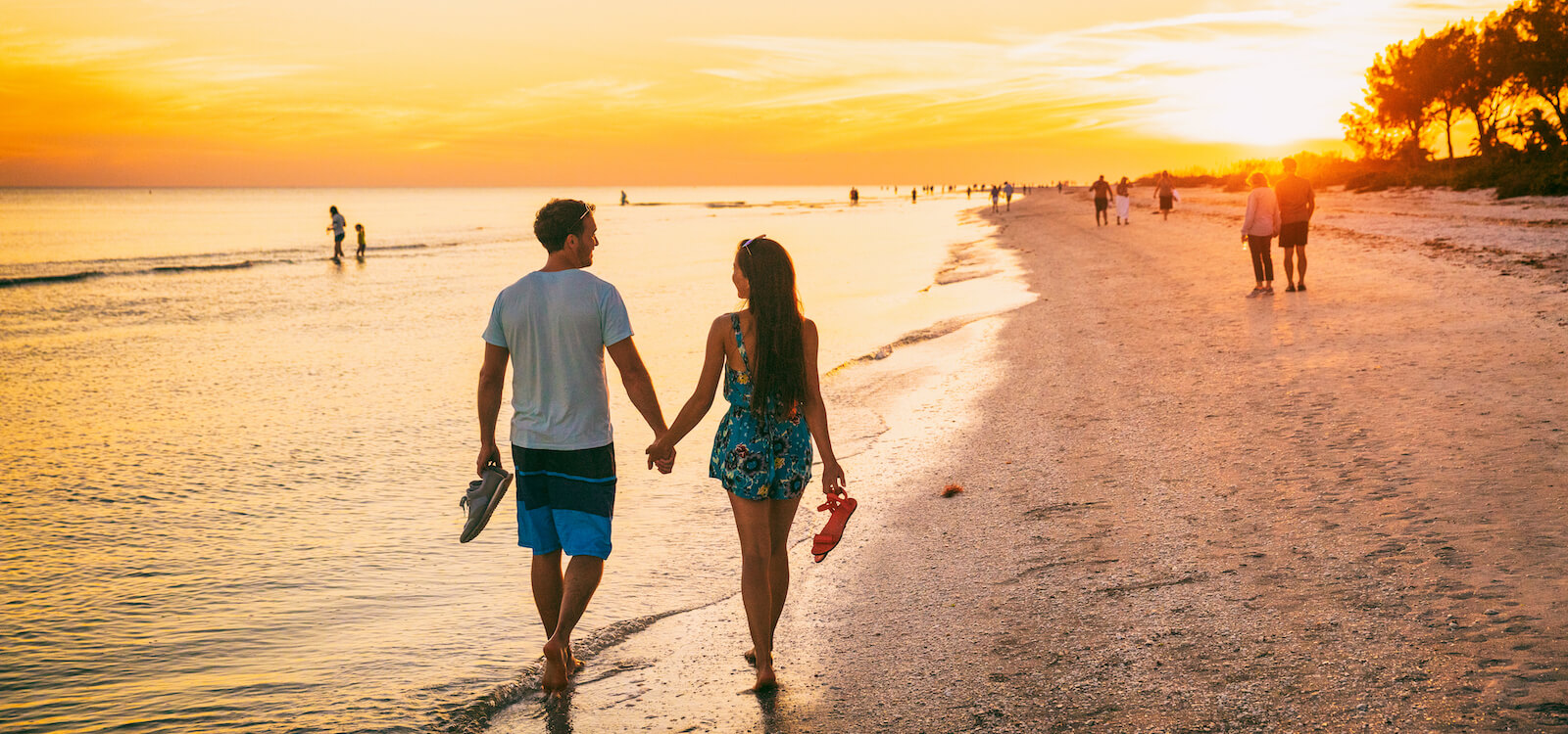 Couple walks hand in hand on the beach during sunset in Fort Myers, Florida. Must Do Visitor Guides | MustDo.com