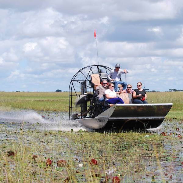Everglades Swamp Tours airboat with passengers glides across the water.