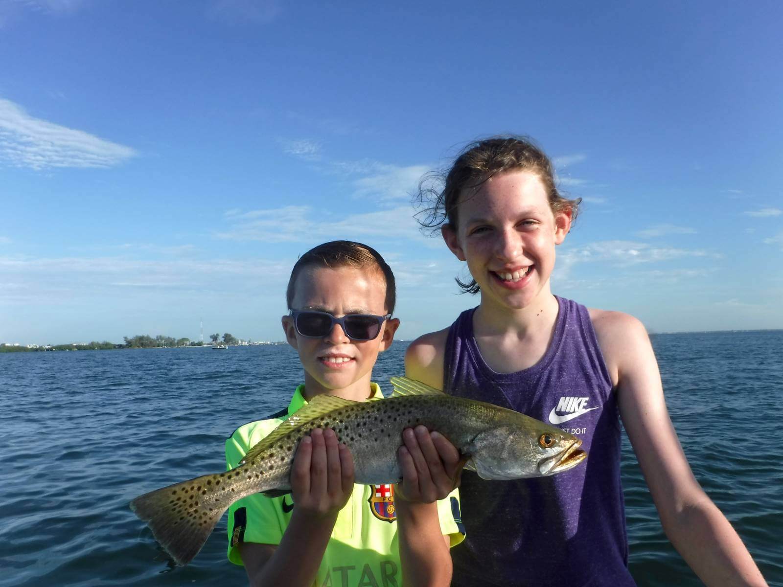 Happy smiling kids hold up a fish caught on a guided fishing trip in Sarasota, Florida. 
