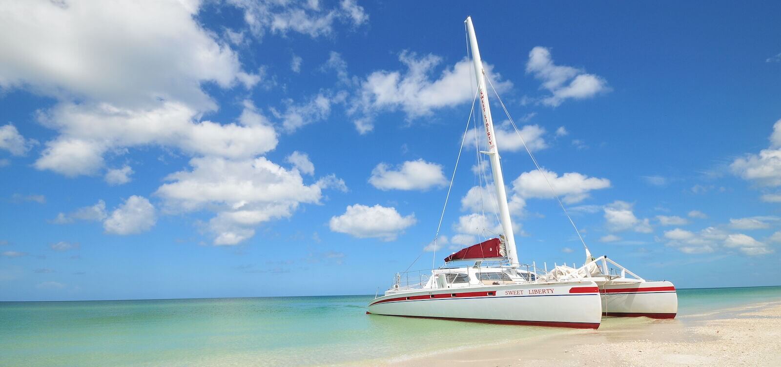 Sweet Liberty charter sail boat on white sand beach in Naples, Florida.