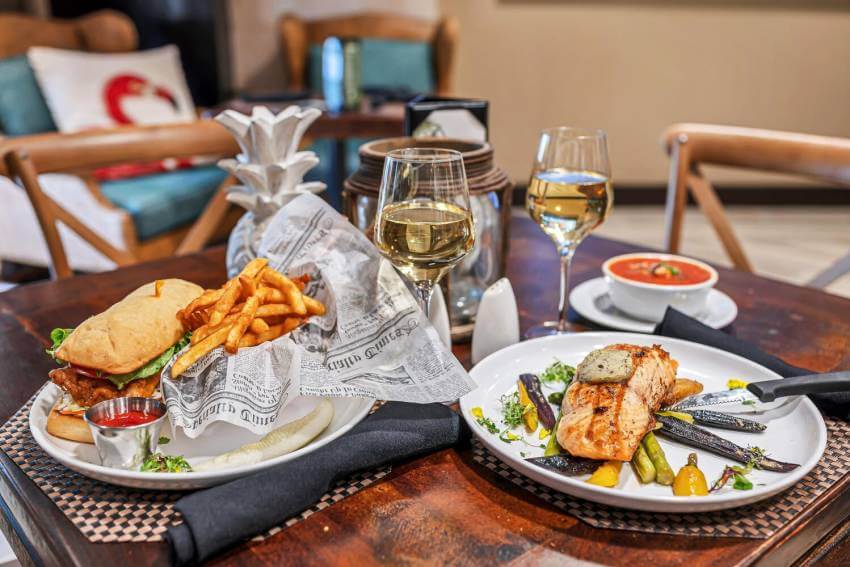 Sandwich with fries entree and grilled salmon entree with white wine indoor dining Bambu Tropical Bar and Grille at Bayfront Inn Naples, Florida