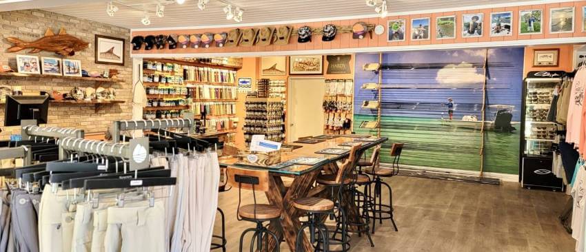Interior of Sanibel's Fly Outfitters store with fishing apparel, gear, rods, and artwork.